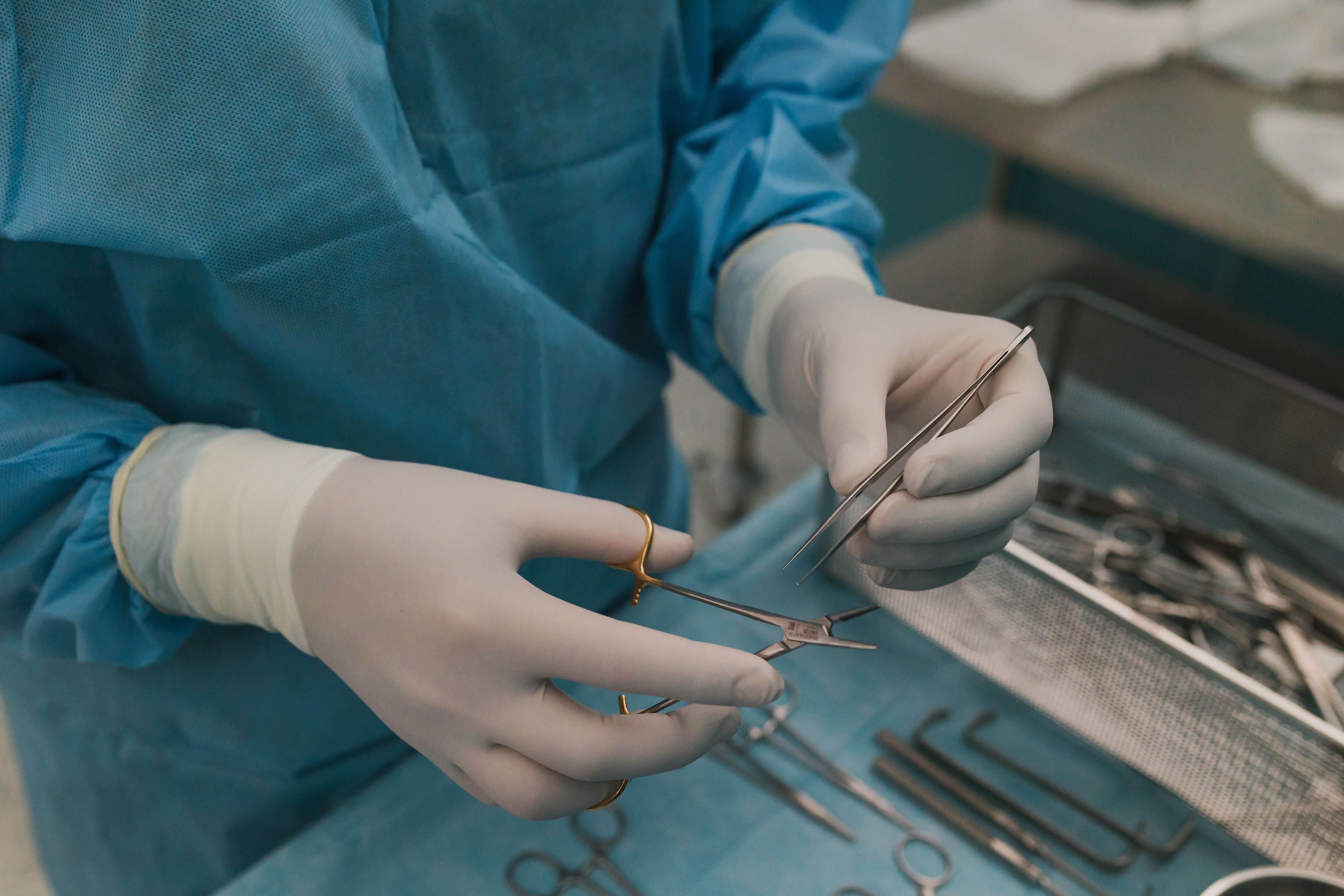 Gloved hands holding fine surgical instruments