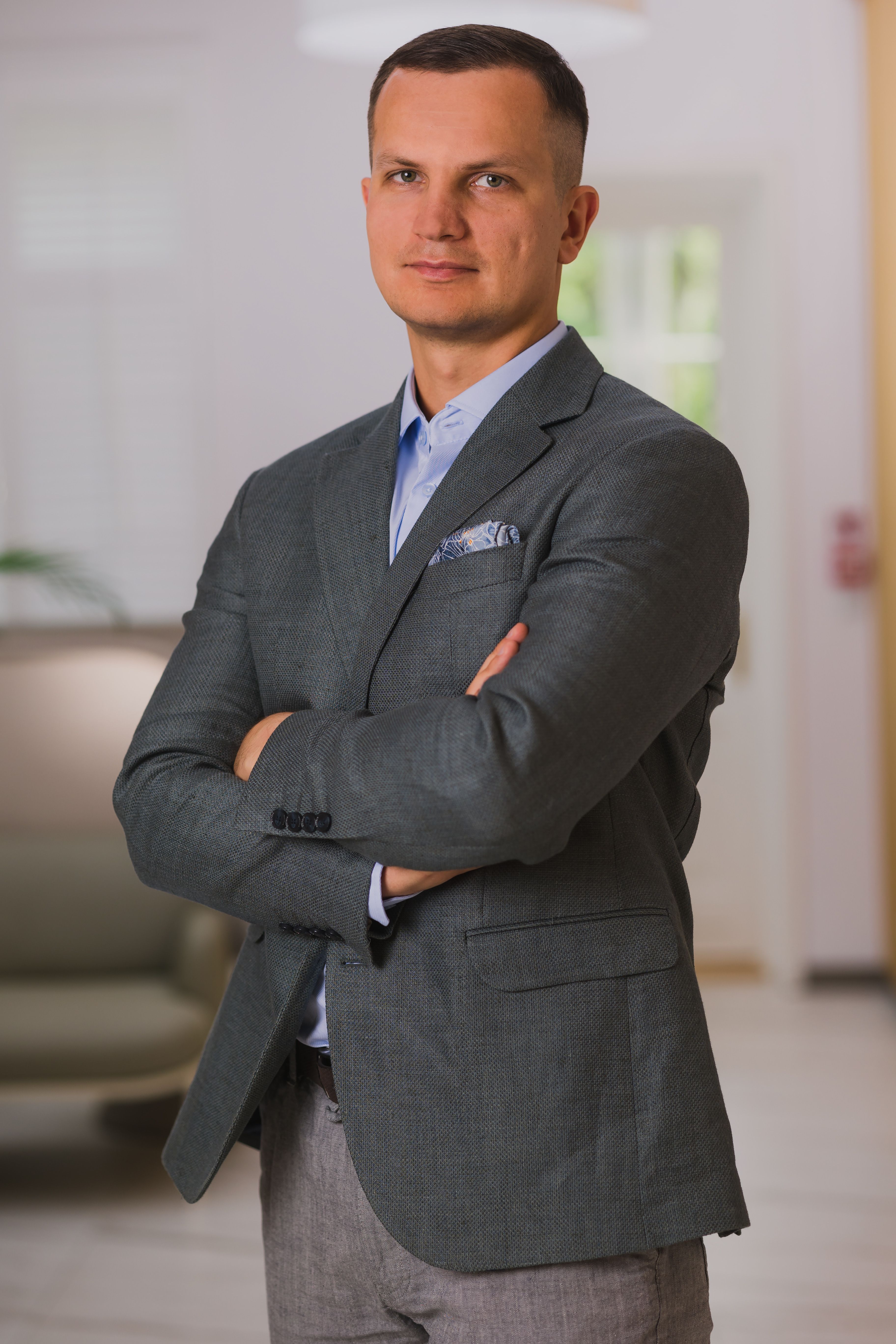 Mateusz Gładysz in a charcoal blazer, arms crossed